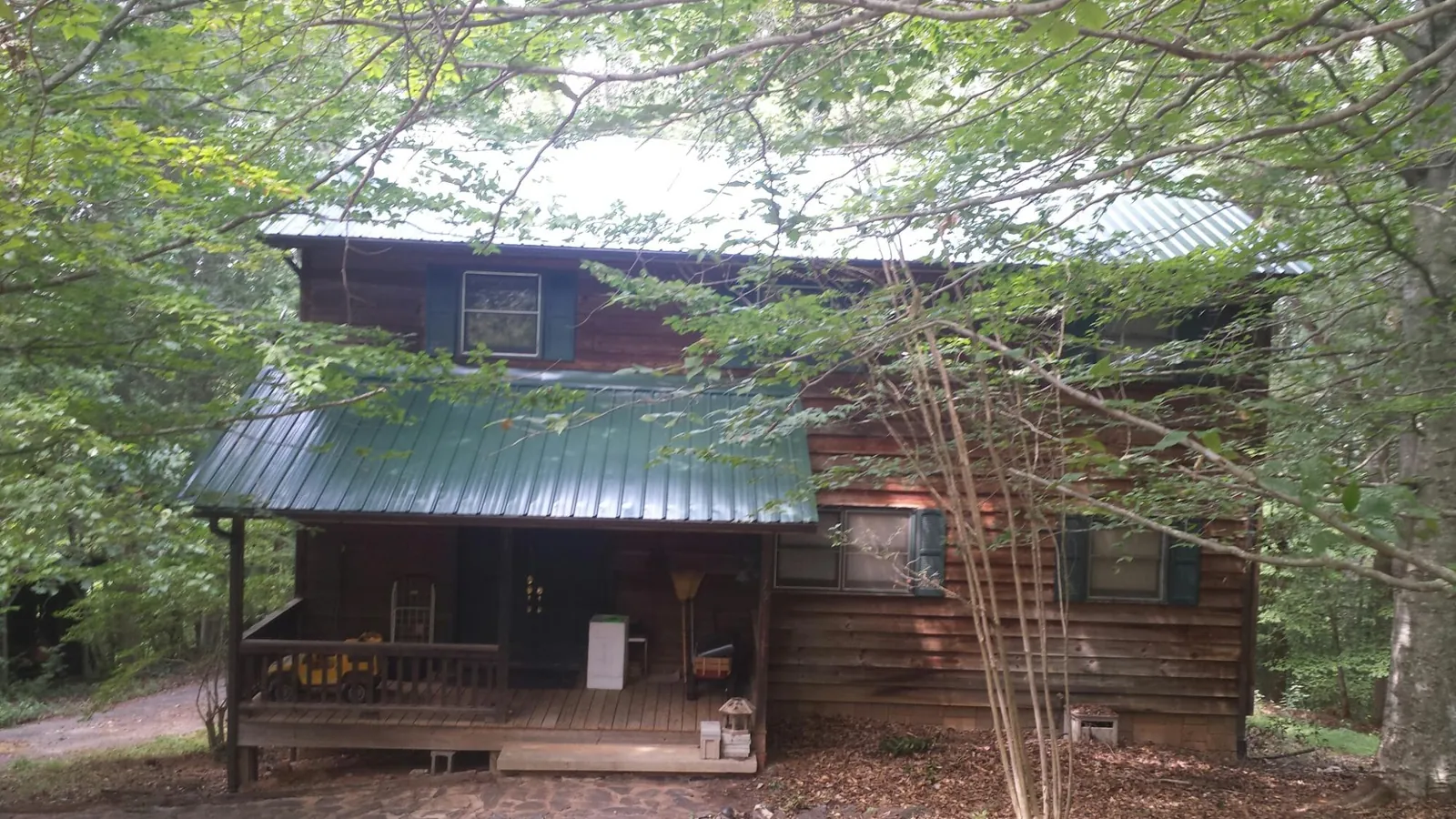 Green metal roof and covered porch on a log cabin in Government Camp