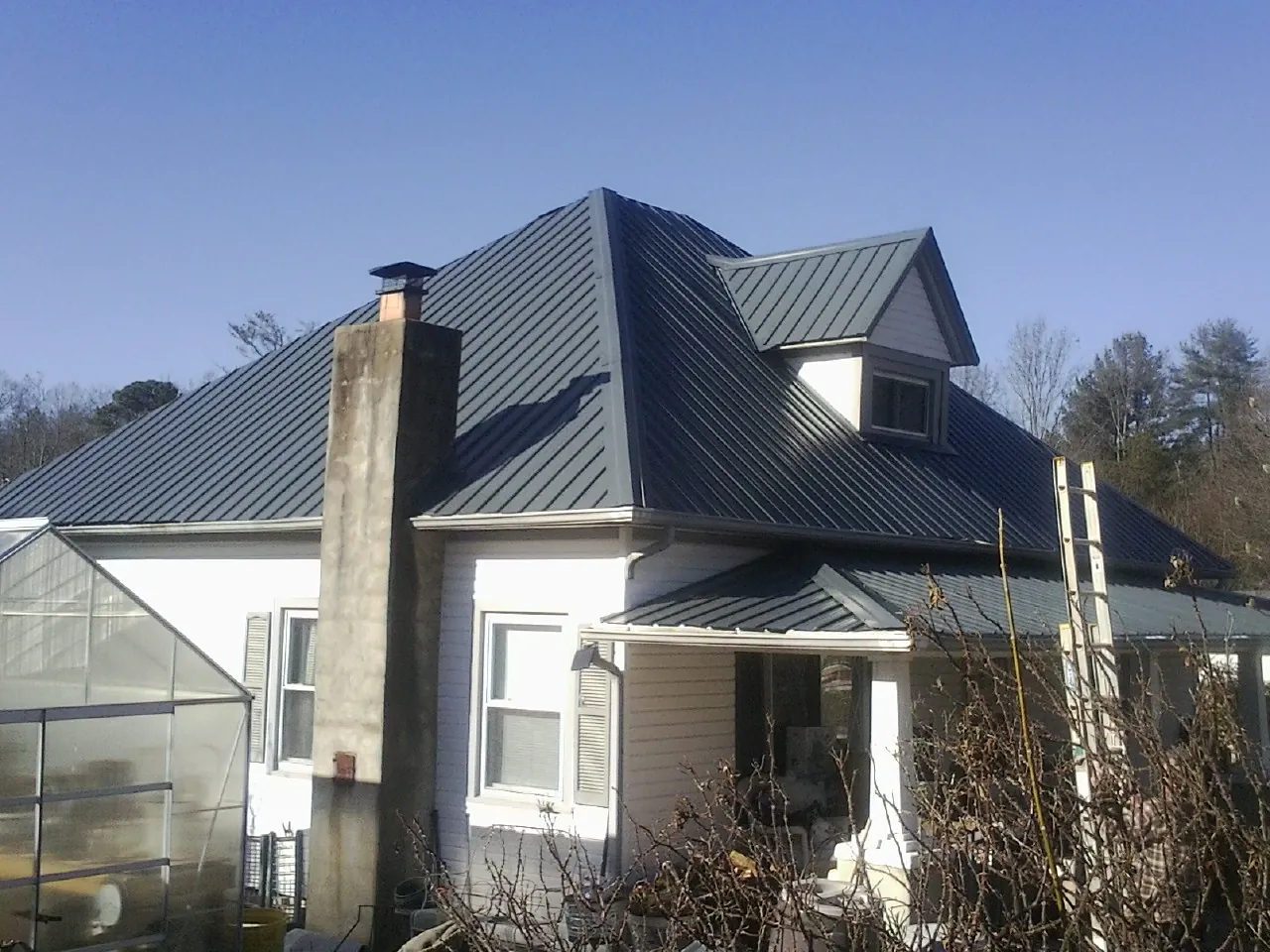 Dark blue standing seam metal roof on a white farmhouse with dormer — Slate & Tile Roof Repair by Roofing Brothers in Government Camp