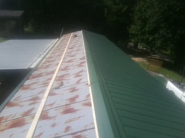 Old rusted panels beside newly installed green metal roofing — Wind Damage Roof Repair by Roofing Brothers in Government Camp