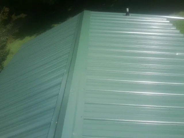 New green metal panels meeting at the ridge of a roof — Flat Roof Repair work by our crew in Government Camp