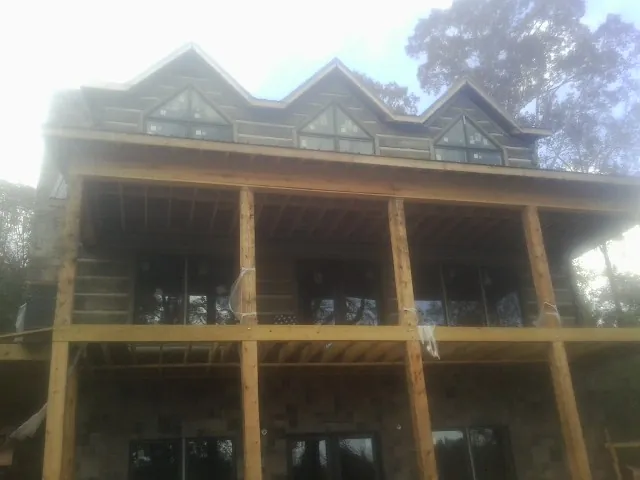 Dormers and porch framing on a large log home under construction — Roof Coating work by our crew in Government Camp