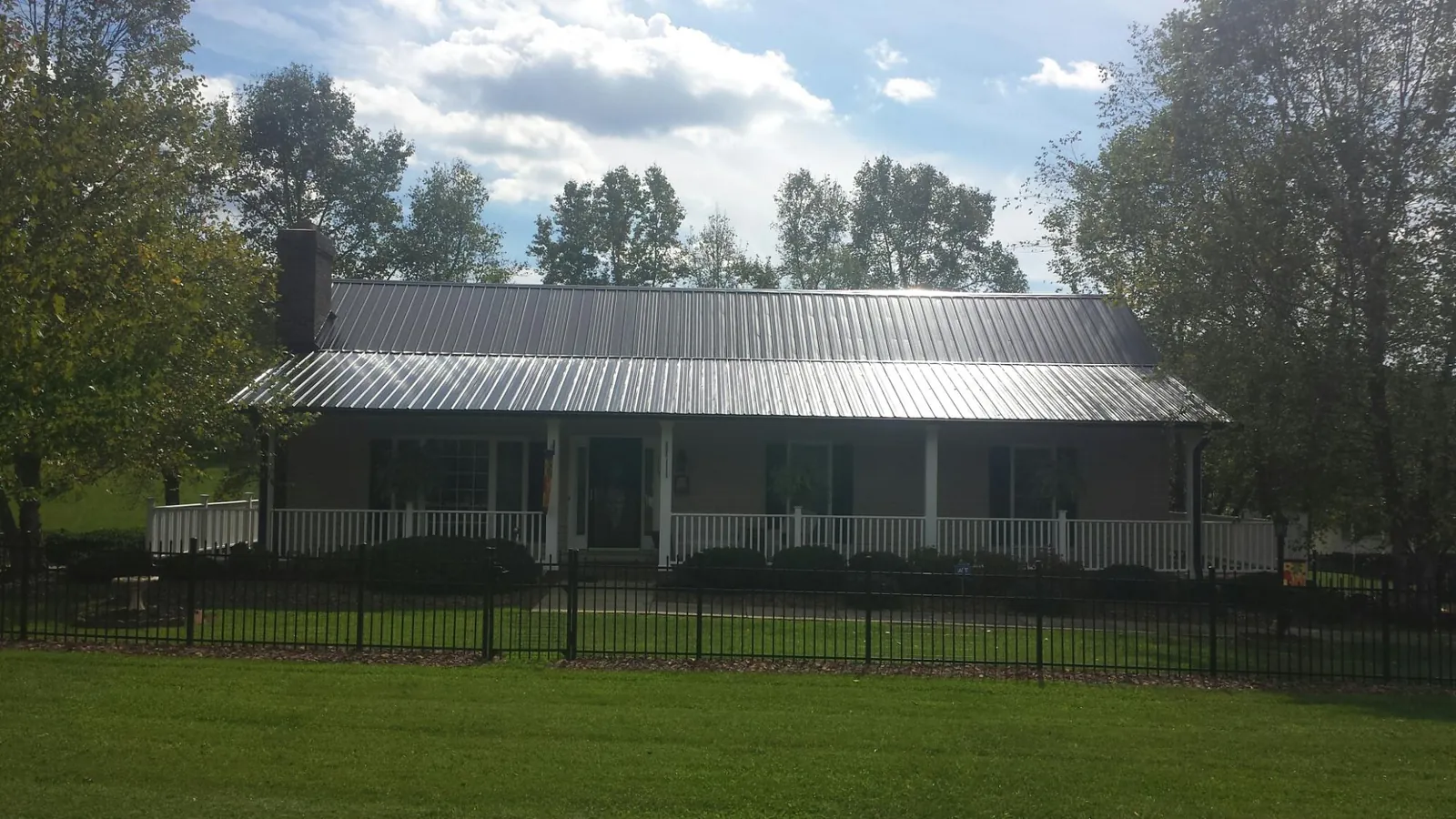 Gray metal roof on a brick ranch with a full width front porch — Gutter Guard Installation work by our crew in Government Camp