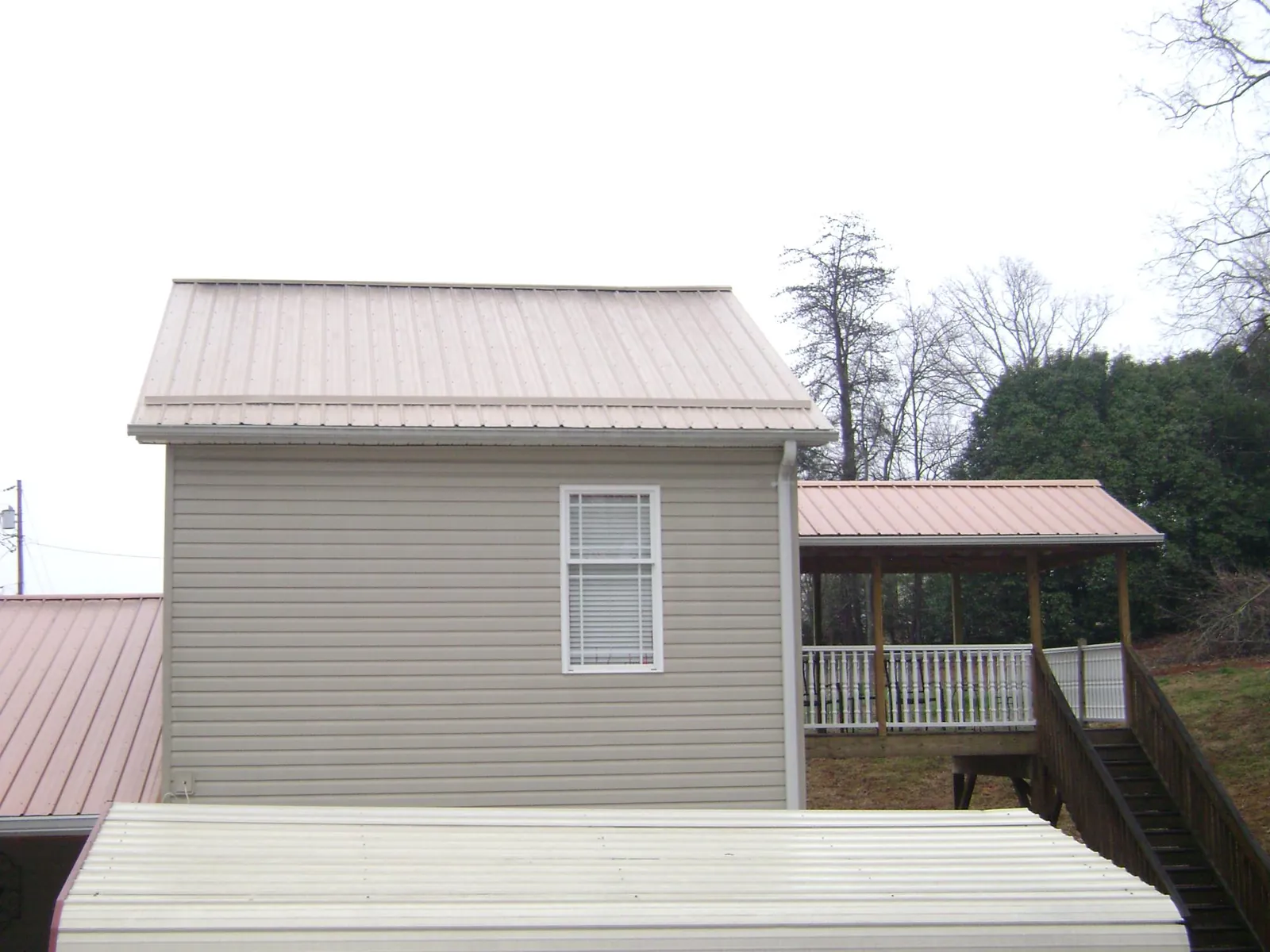 Tan metal roofs on a two story addition and attached porch, from a Roof Replacement job in Government Camp