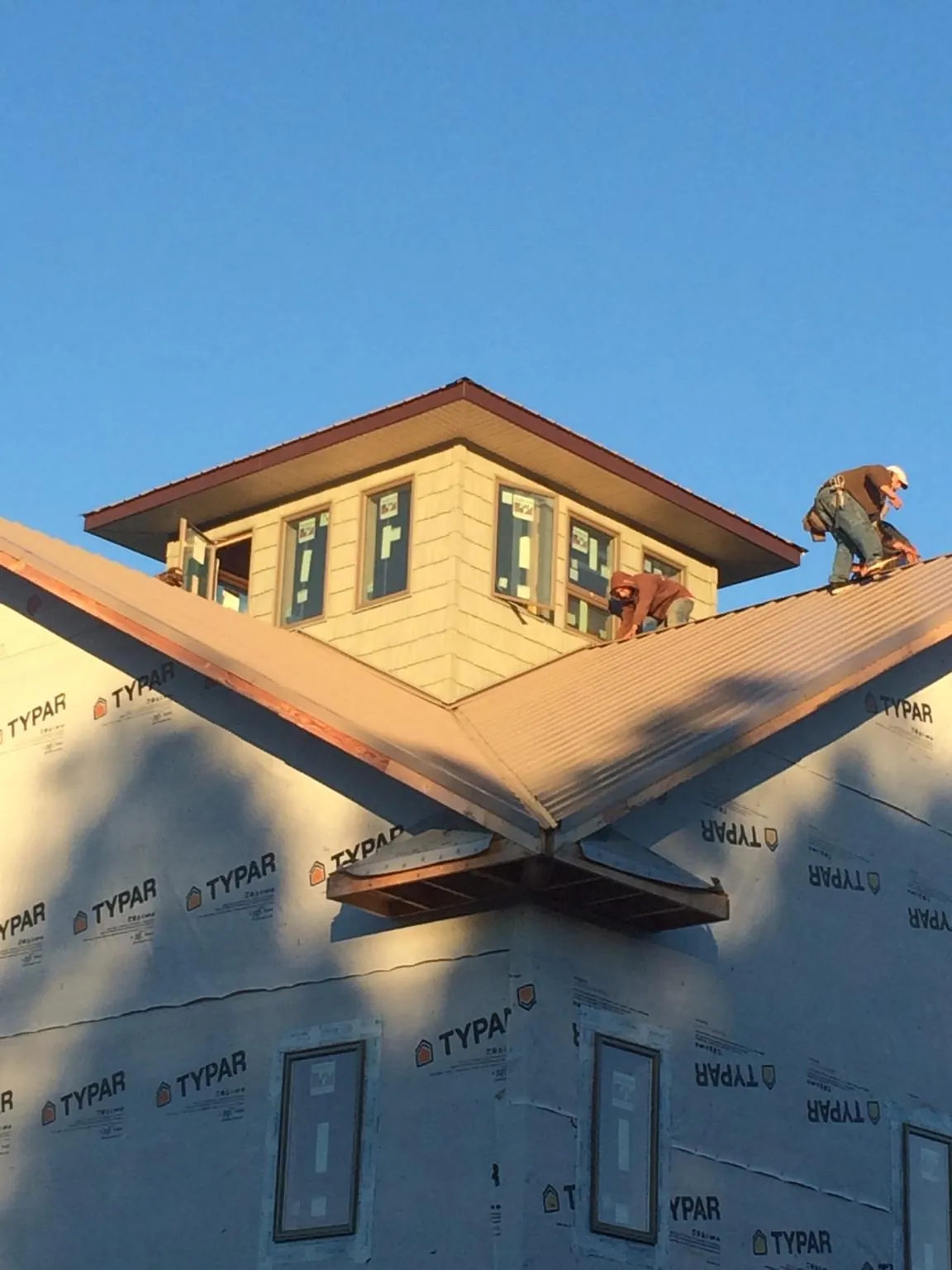 Roofers working around a rooftop cupola on a new metal roof at sunset — Roof Waterproofing in Government Camp by Roofing Brothers